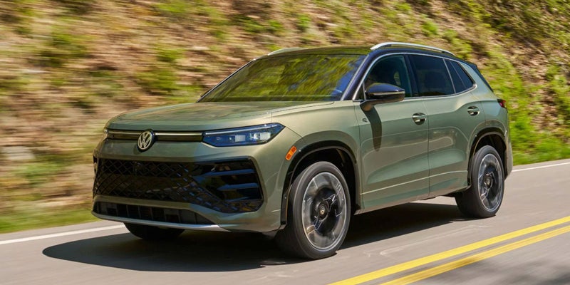 Green 2026 Volkswagen Tiguan driving on a winding road.